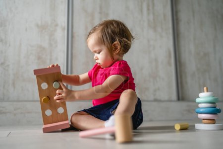 Foto de One child small caucasian girl little toddler playing with educational toys at home childhood and growing up early development concept copy space side view - Imagen libre de derechos