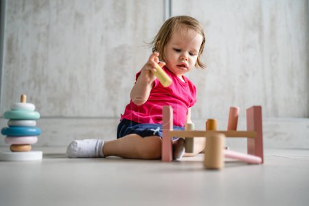 Photo for One child small caucasian girl little toddler playing with educational toys at home childhood and growing up early development concept copy space front view - Royalty Free Image