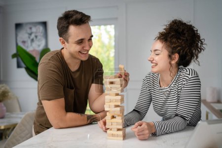 Photo for Woman and man happy caucasian couple husband and wife or friends playing jenga table game at home having fun happy smile leisure time spending time together family time copy space real people - Royalty Free Image
