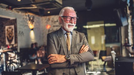 Téléchargez les photos : Portrait d'un homme d'affaires senior debout dans un café ou un restaurant - en image libre de droit