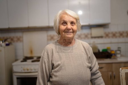 Photo for One woman senior old female caucasian pensioner standing at home waist up portrait looking to the camera dementia alzheimer's disease concept positive emotion copy space - Royalty Free Image
