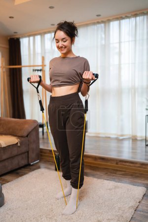 Foto de One woman beautiful caucasian female training at home in room using rubber resistance bands tubes sportswoman doing exercises alone health and fitness concept copy space - Imagen libre de derechos