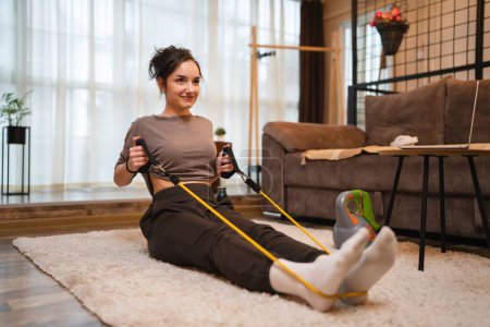 Foto de One woman beautiful caucasian female training at home in room using rubber resistance bands tubes sportswoman doing exercises alone health and fitness concept copy space - Imagen libre de derechos