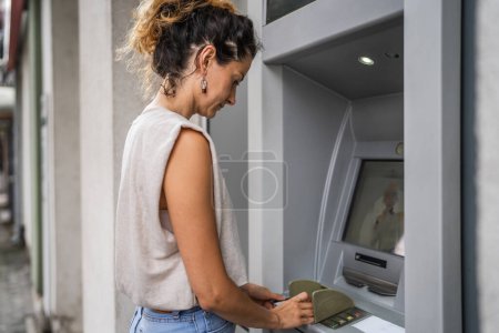 Photo for Woman using credit card and withdrawing cash at the ATM - Royalty Free Image
