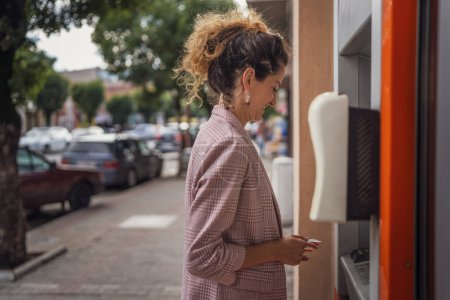 Foto de Mujer usando tarjeta de crédito y retirando efectivo en el cajero automático - Imagen libre de derechos