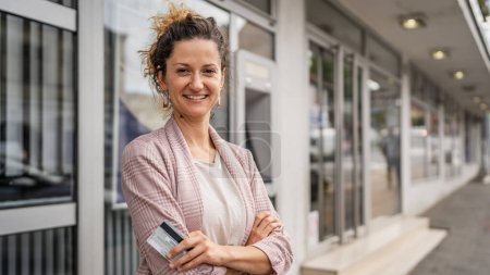 Photo for Portrait of adult caucasian woman stand in front of ATM machine hold credit or debit card - Royalty Free Image