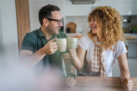 Photo for Young couple caucasian man and woman husband and wife enjoy cup of tea or coffee in the morning at home happy smile daily morning routine real people - Royalty Free Image