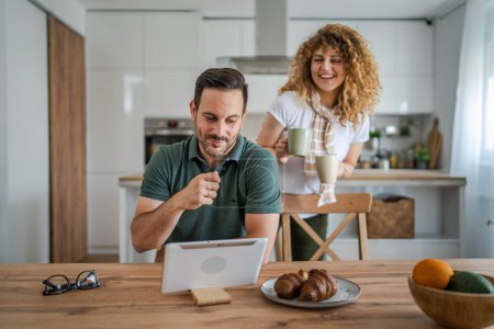 Photo for Young couple caucasian man and woman husband and wife enjoy cup of tea or coffee in the morning at home happy smile daily morning routine real people - Royalty Free Image