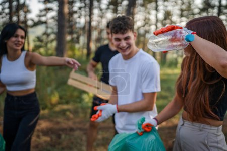 Foto de Grupo de amigos adolescentes gen Z hombres y mujeres caucásicos mujeres recogiendo basura botellas de plástico y papel del bosque limpiando la naturaleza en el concepto de ecología de cuidado ambiental de día soleado - Imagen libre de derechos
