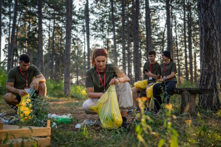 Photo for Group of teenage friends gen Z male and female caucasian men women picking up waste garbage plastic bottles and paper from the forest cleaning up nature in sunny day environmental care ecology concept - Royalty Free Image