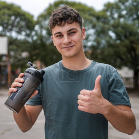 Téléchargez les photos : Un jeune homme caucasien adolescent tenir supplément shaker stand extérieur - en image libre de droit