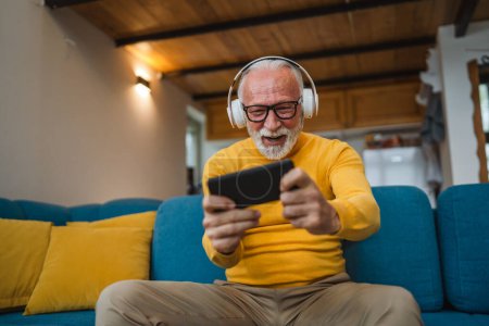 Photo for One senior old caucasian man sit at home happy smile play video games leisure activity having fun hold mobile phone smartphone have fun copy space - Royalty Free Image