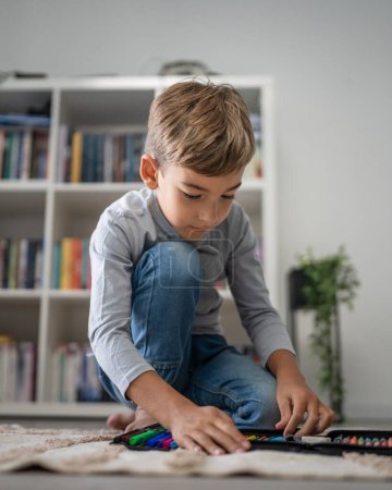 Photo for Small caucasian boy pupil child prepare his backpack for first day of school back to school and education concept sit on the floor at home packing his stuff real people copy space - Royalty Free Image