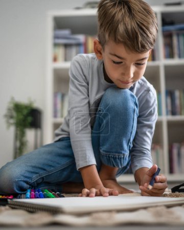 Téléchargez les photos : Un écolier Petit garçon caucasien jouer à la maison dessiner sur le sol faire des devoirs développement de l'enfance grandir et l'éducation concept copier espace vie domestique - en image libre de droit