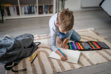 Photo for A schoolboy Small caucasian boy play at home draw on the floor doing homework childhood development growing up and education concept copy space domestic life - Royalty Free Image