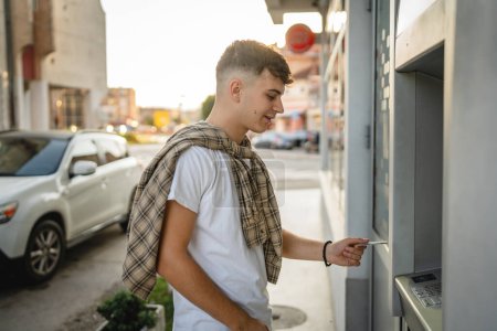 Photo for Man teenage student using credit card and withdrawing cash at the ATM - Royalty Free Image