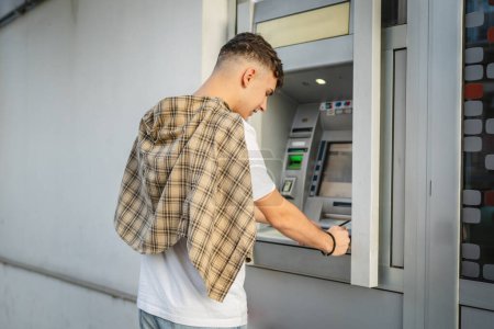 Photo for Man teenage student using credit card and withdrawing cash at the ATM - Royalty Free Image