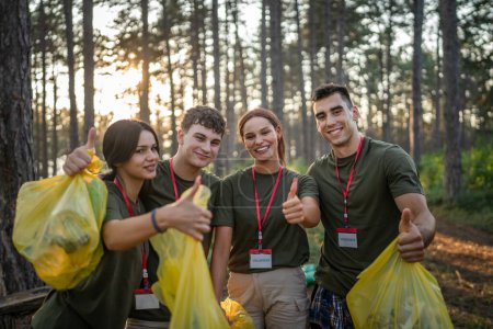 Téléchargez les photos : Portrait d'un groupe d'amis bénévoles se préparent à ramasser les déchets et la nature propre de la forêt dans la journée d'été au ralenti - en image libre de droit