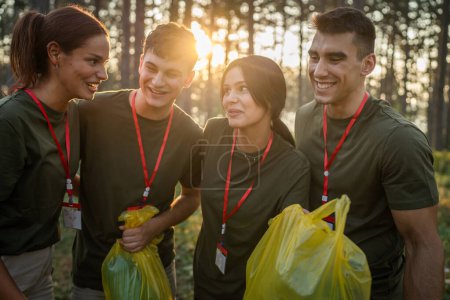 Téléchargez les photos : Portrait d'un groupe d'amis bénévoles se préparent à ramasser les déchets et la nature propre de la forêt dans la journée d'été au ralenti - en image libre de droit