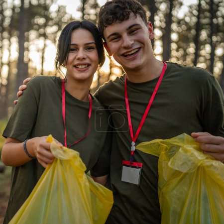 Téléchargez les photos : Portrait couple se préparer à recueillir les déchets et propre forêt nature en été jour ralenti - en image libre de droit