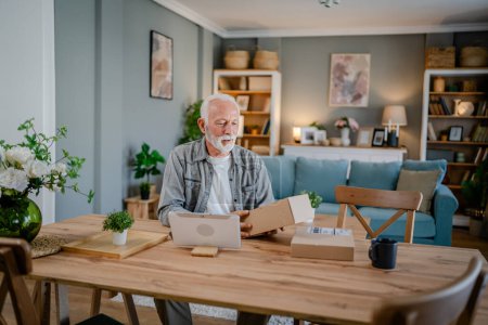 Photo for One senior caucasian man at home hold cardbox package delivered gift or order - Royalty Free Image