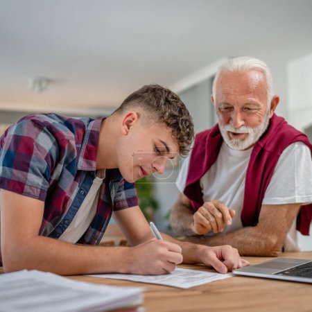One student teenage caucasian man teen study learn with help of his tutor professor or grandfather senior man at home having private lesson to prepare for exam education concept real people copy space