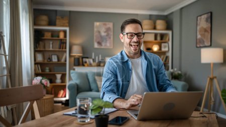 Téléchargez les photos : Un homme adulte caucasien mâle avec barbe travail sur son ordinateur portable à la maison heureux sourire succès entrepreneur indépendant ou concept de travail à distance - en image libre de droit