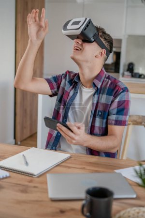 Foto de Chico caucásico adolescente joven estudiante disfrutar de realidad virtual VR auriculares en casa mientras tomar un freno - Imagen libre de derechos