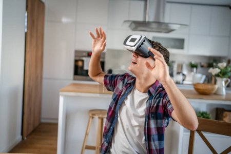 Photo for Boy caucasian teenager young man student enjoy virtual reality VR headset at home while take a brake - Royalty Free Image