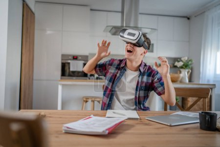 Photo for Boy caucasian teenager young man student enjoy virtual reality VR headset at home while take a brake - Royalty Free Image