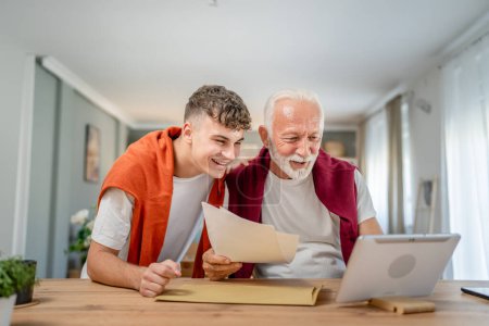 Photo for Senior man grandfather and caucasian man teenager boy grandson receive letter read good news student get scholarship or invitational letter from university share excitement real people - Royalty Free Image