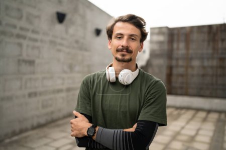 Photo for One man young adult caucasian male front view portrait of modern person with mustaches wear headphones looking to the camera real people copy space waist up standing confident outdoor in day - Royalty Free Image