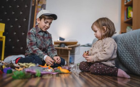 Photo for Small caucasian boy and girl siblings brother and sister children play at home sit on the floor at home childhood development growing up concept copy space domestic life - Royalty Free Image