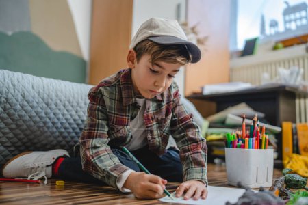 Foto de One small caucasian boy Gradeschooler child draw with crayon at home - Imagen libre de derechos