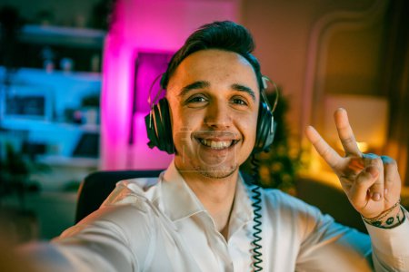 Self portrait of one man caucasian male streamer blogger or content creator with headphones on his head happy smile confident in his studio copy space user generated content UGC