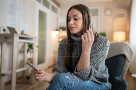 Foto de One woman young caucasian female hold medicine drugs pills tablets while siting at home smoke cigarette thinking trying to quit smoking real person copy space - Imagen libre de derechos