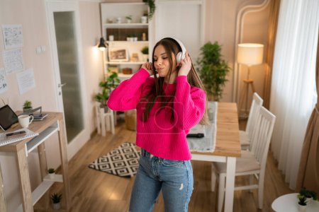 Photo for One woman young caucasian female teenager dancing alone at home with headphones on her head having fun while listen to the music happy smile real people copy space - Royalty Free Image