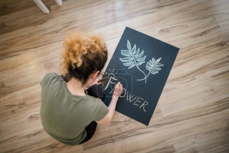 Téléchargez les photos : Une femme artiste designer dessiner sur le tableau sur le sol avec de la craie - en image libre de droit