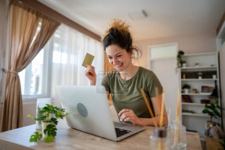 Photo for One woman adult caucasian female sit at home happy smile at laptop computer hold bank credit card online shopping concept real people copy space e-commerce - Royalty Free Image