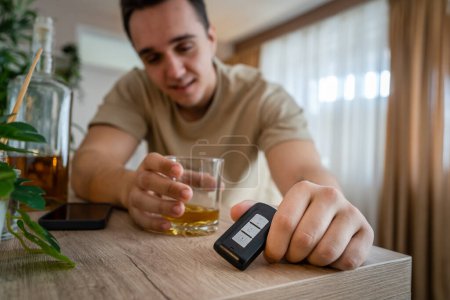 Photo for One man sit at home with bottle of liquor drink whiskey drunk alcoholic Alcohol abuse, addiction and man depression concept drink and drive copy space hold car keys - Royalty Free Image