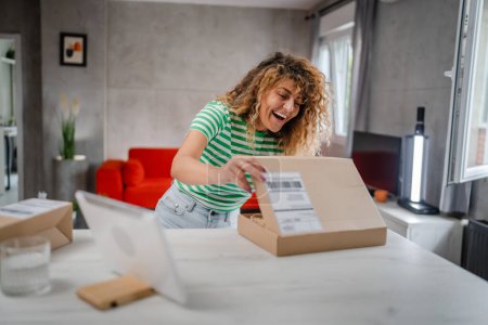 Téléchargez les photos : Une femme heureuse boîte de paquet de carton de courrier ouvert présente à la maison - en image libre de droit
