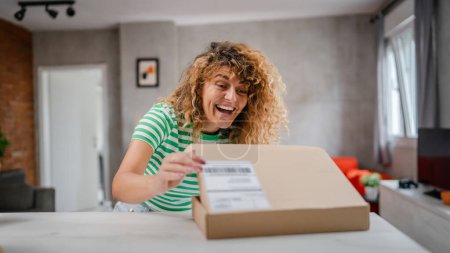 Foto de Una mujer feliz caja de cartón abierta de correo electrónico presente en casa - Imagen libre de derechos