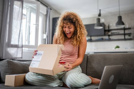 Téléchargez les photos : Une femme heureuse boîte de paquet de carton de courrier ouvert présente à la maison - en image libre de droit