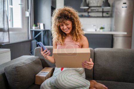 Photo for One caucasian woman use smart phone to check shipping details of the received package online shopping product arrived stand with smartphone app application check online details happy smile - Royalty Free Image