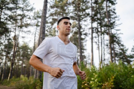 Photo for One man young caucasian male athlete running trough the woods in nature outdoor jogging in autumn or summer day sport fitness and recreation healthy lifestyle concept real people copy space - Royalty Free Image