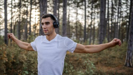 Photo for One man young caucasian male athlete stretch in the woods in nature outdoor jogging or exercise in autumn or summer day sport fitness and recreation healthy lifestyle concept real people copy space - Royalty Free Image