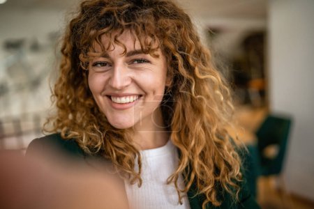 Photo for One woman caucasian female happy confident stand indoor at cafe with curly hair smile real person copy space self portrait selfie UGC User Generated Content - Royalty Free Image