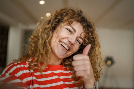 Foto de Una mujer caucásica mujer feliz seguro de pie interior en la cafetería con el pelo rizado sonrisa persona real copia espacio autorretrato selfie UGC usuario contenido generado - Imagen libre de derechos