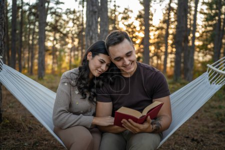 Photo for Man and woman young adult couple in nature hold and read book in love - Royalty Free Image