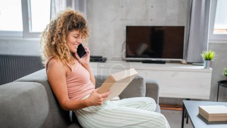 Photo for One woman caucasian adult female receive presents in box open read card happy smile in front of laptop computer at home having online video call - Royalty Free Image